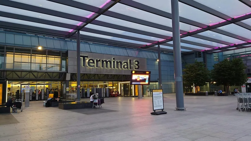 Forecourt and entrance of Heathrow Terminal 3 at dusk under a glass canopy