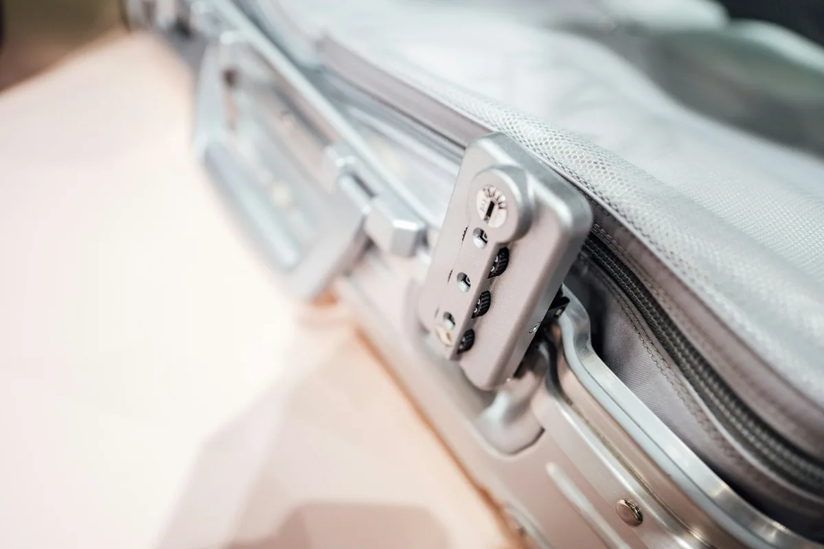 Close-up of a combination lock on the zip of a silver hard-shell cabin suitcase