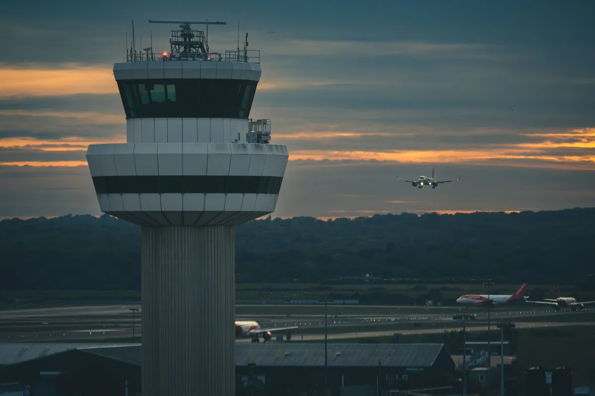 Gatwick control tower at dusk with an easyJet plane approaching the runway
