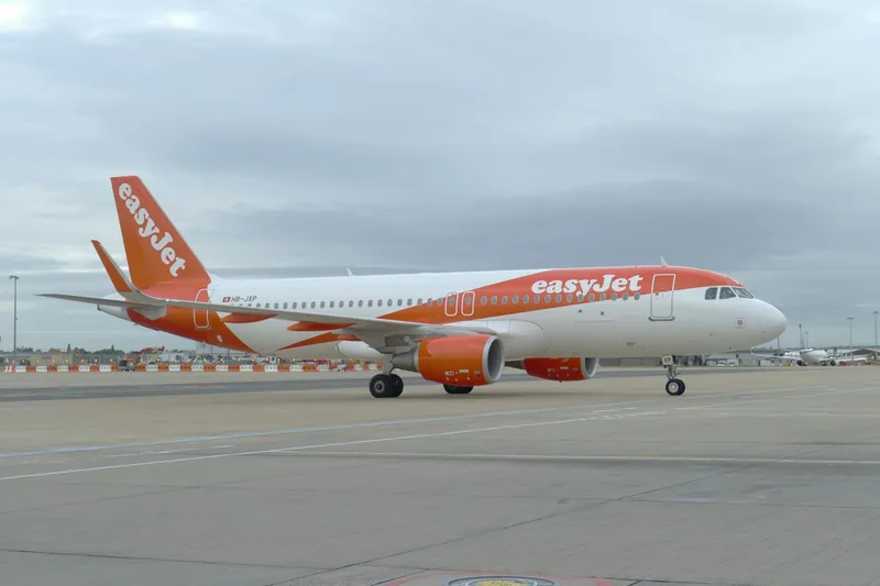 An orange and white easyJet Airbus taxiing on the apron at Gatwick Airport