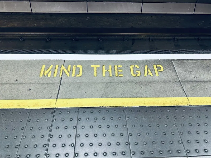 Yellow Mind the Gap lettering painted along the edge of a Heathrow Express platform