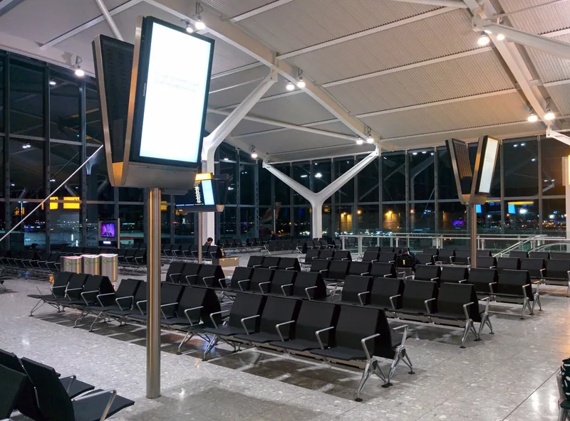 Rows of empty seats in a quiet Heathrow gate area at night