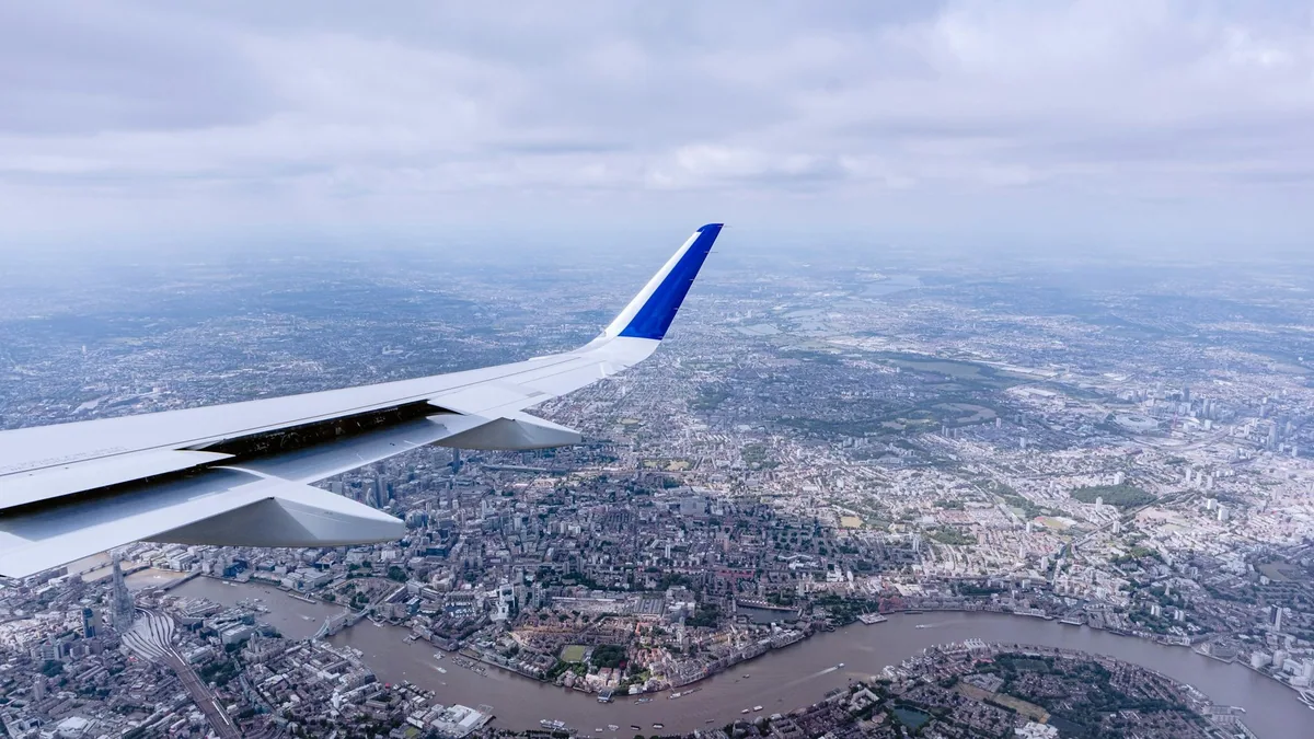 View from a plane window of the wing over London and the winding River Thames