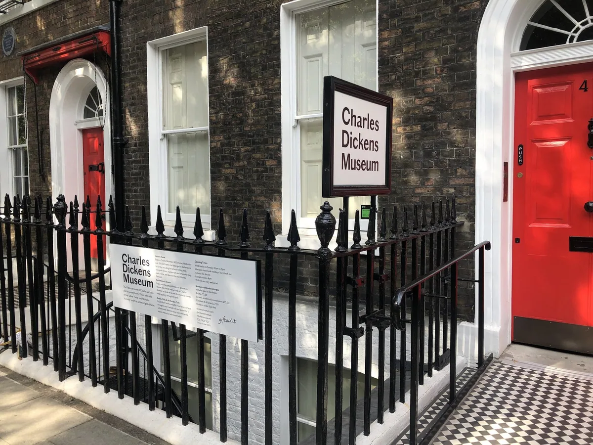 The red front door and Charles Dickens Museum sign behind black railings on Doughty Street