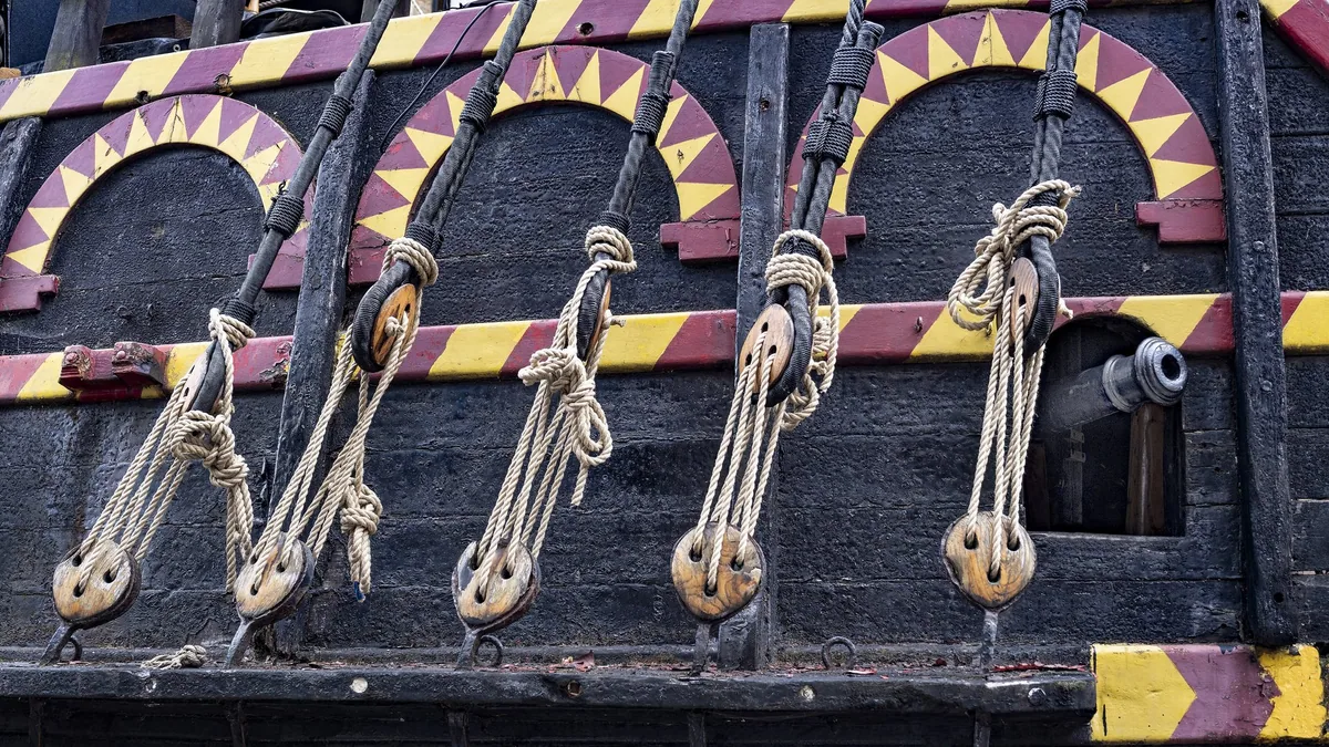 Deadeyes, lanyards and a gun port on the painted black and yellow hull of the Golden Hinde
