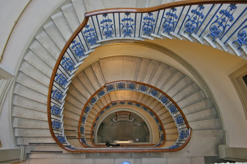 The spiral stone staircase at the Courtauld Gallery seen from below, with its blue and white ironwork balustrade