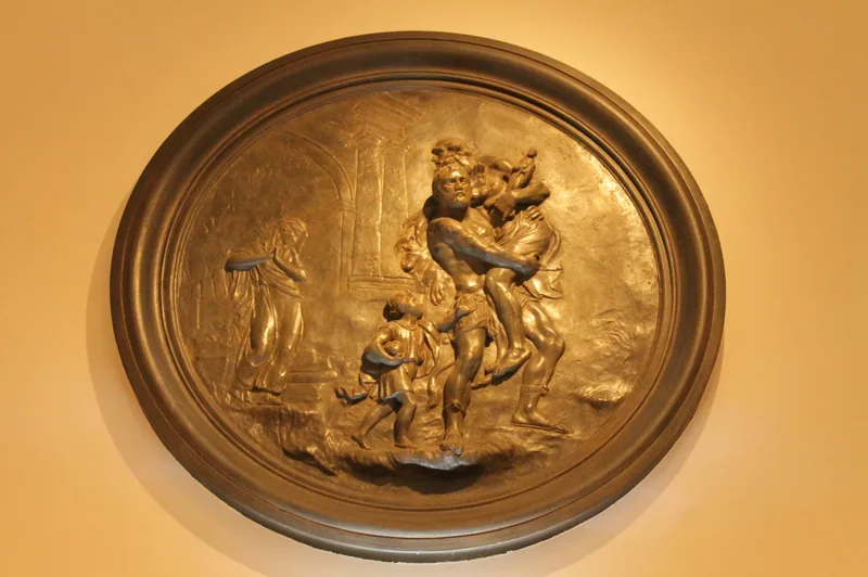 A gilded circular relief of the flight of Aeneas from Troy on a wall in the Foundling Museum