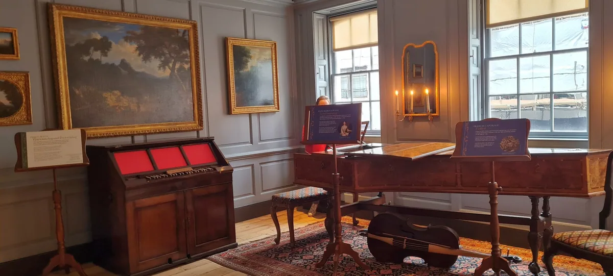 Handel's panelled music room at 25 Brook Street with a harpsichord, music stands and a cello case on the floor