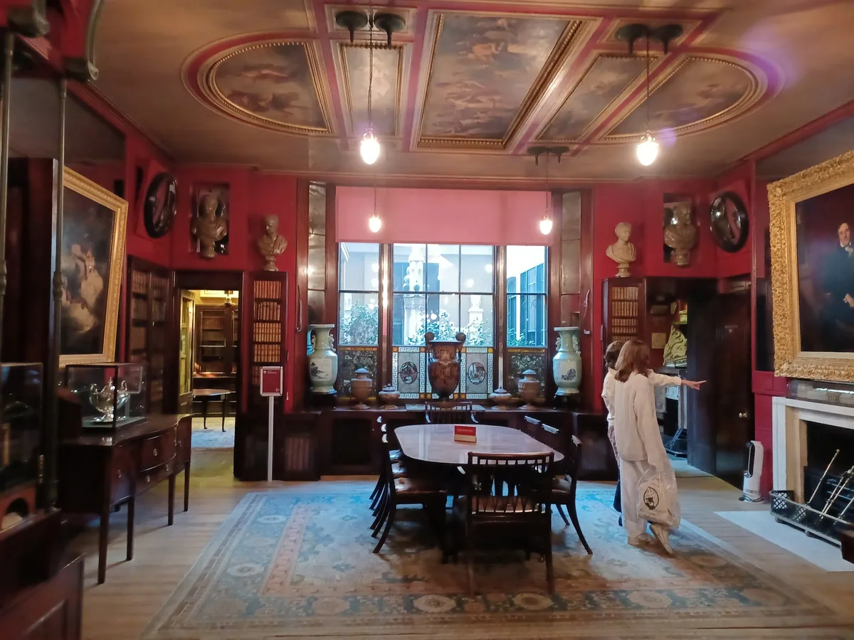 The red dining room at Sir John Soane's Museum, with a painted ceiling, busts, paintings and a long table