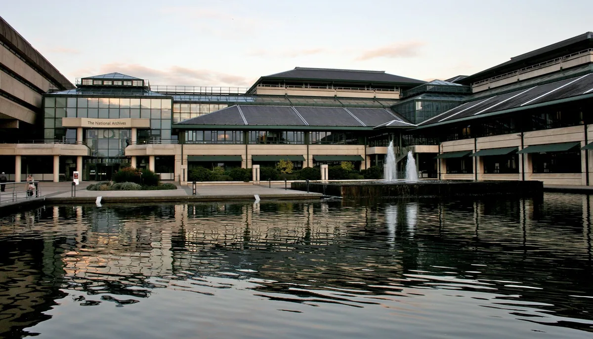 The National Archives at Kew reflected in its lake, with a fountain playing and the glazed entrance range behind