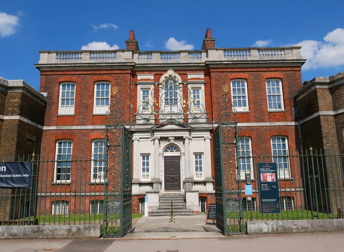 Red-brick Georgian front of Ranger's House in Greenwich, seen through its ornate open iron gates from Chesterfield Walk