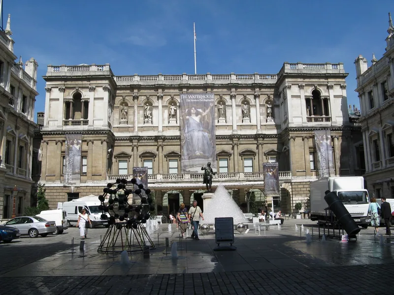 The courtyard of Burlington House with exhibition banners and a sculpture on the paving