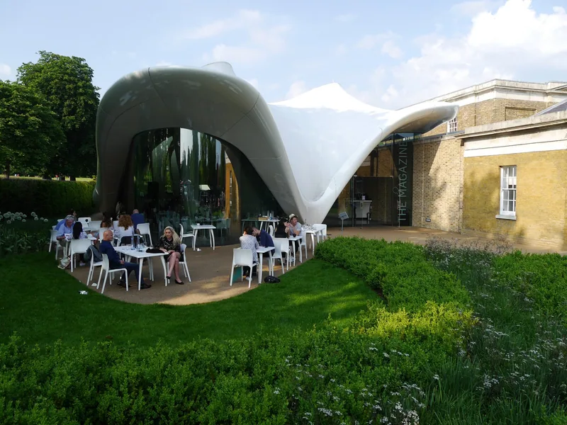 The Serpentine North gallery with its white curving roof extension and tables set out on the lawn