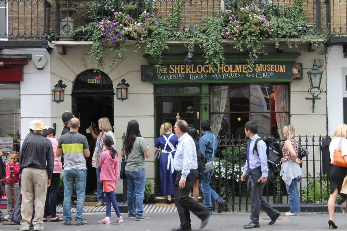 Visitors queueing outside the green shopfront and door of the Sherlock Holmes Museum at 221b Baker Street