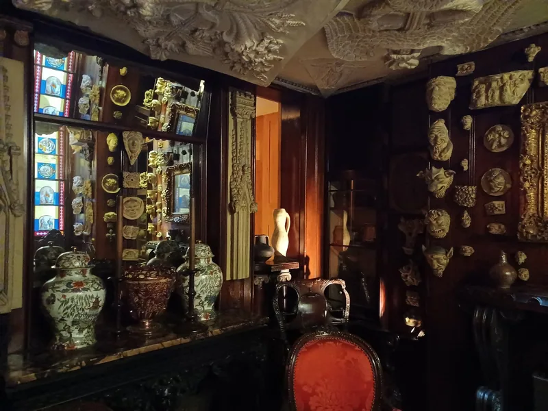 A dimly lit room at Sir John Soane's Museum crowded with vases, plaster casts and stained glass