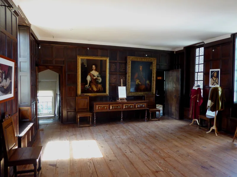 The oak-panelled Great Chamber inside Sutton House, hung with two portraits and displaying period costume on stands
