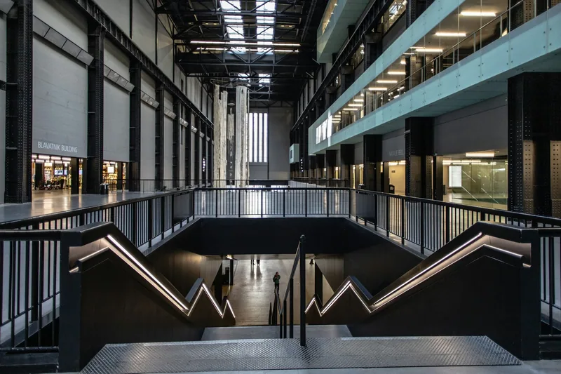 Staircase descending into the empty Turbine Hall inside Tate Modern, with balconies along one side