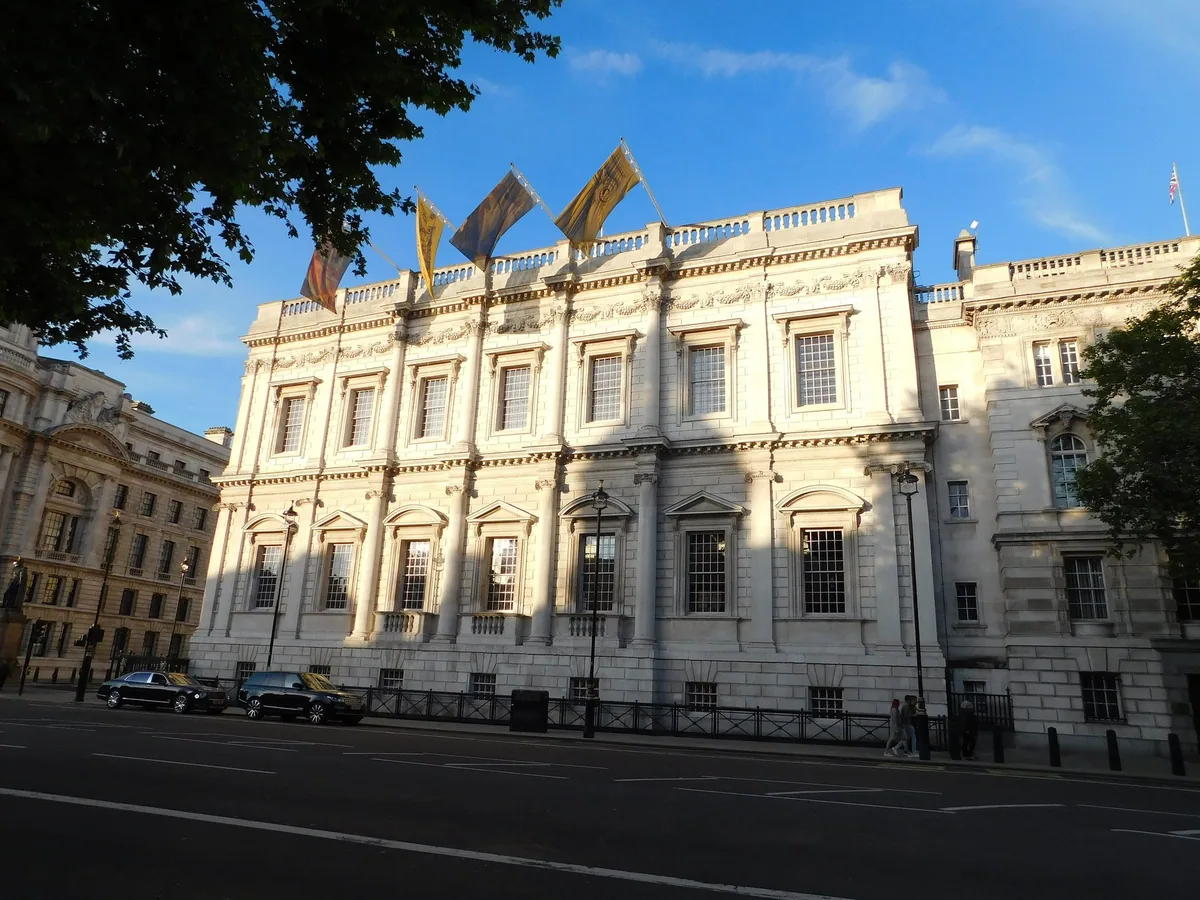 The Palladian stone front of the Banqueting House on Whitehall in evening light, flags flying from the roof