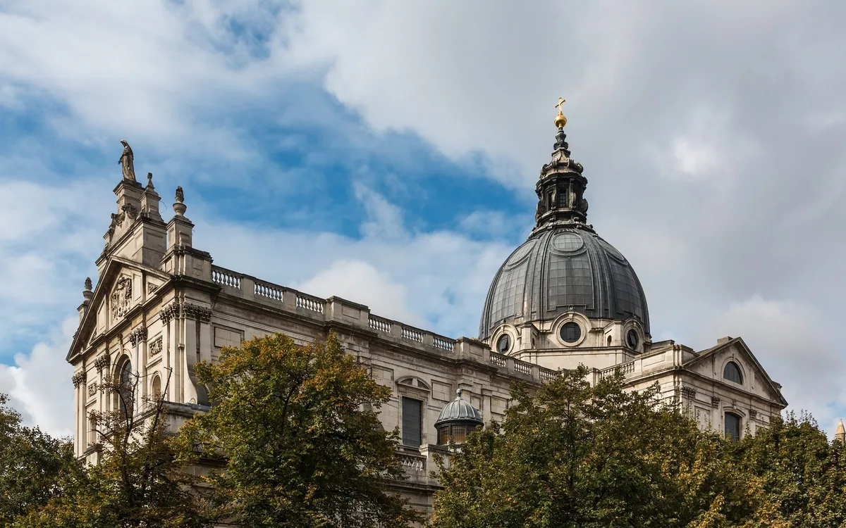 The lead dome and Italianate stone facade of the Brompton Oratory rising above street trees