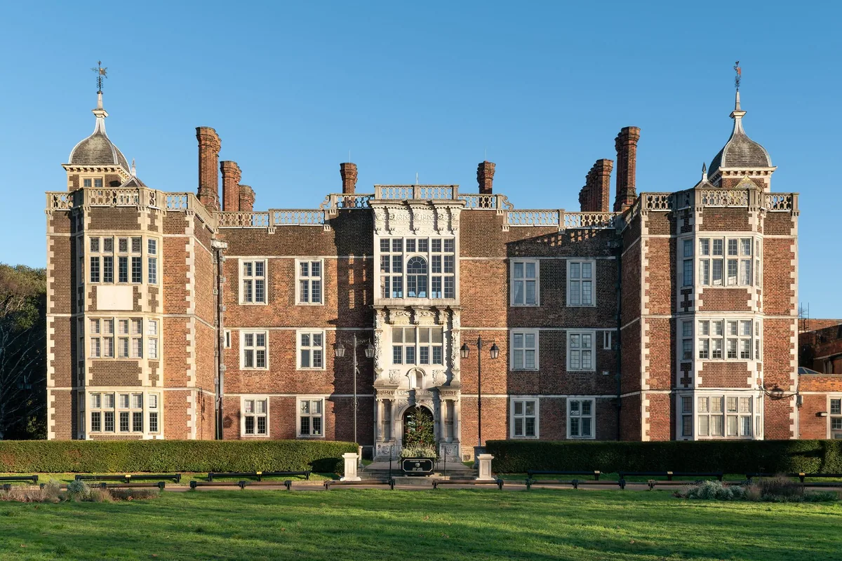 The symmetrical red-brick front of Charlton House, a Jacobean manor with stone quoins, tall bay windows and a carved centre porch