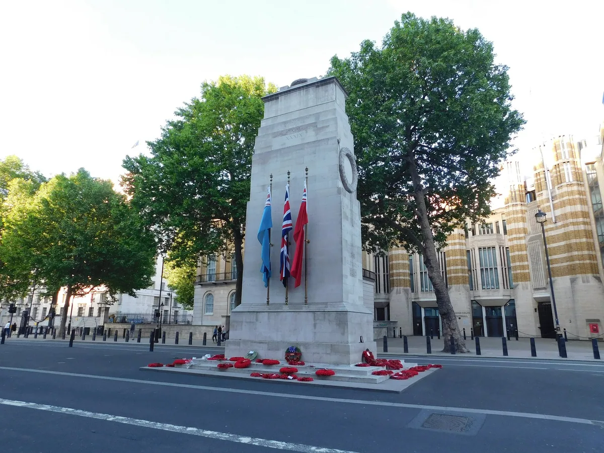 The Cenotaph standing in the middle of Whitehall, with flags and poppy wreaths at its base