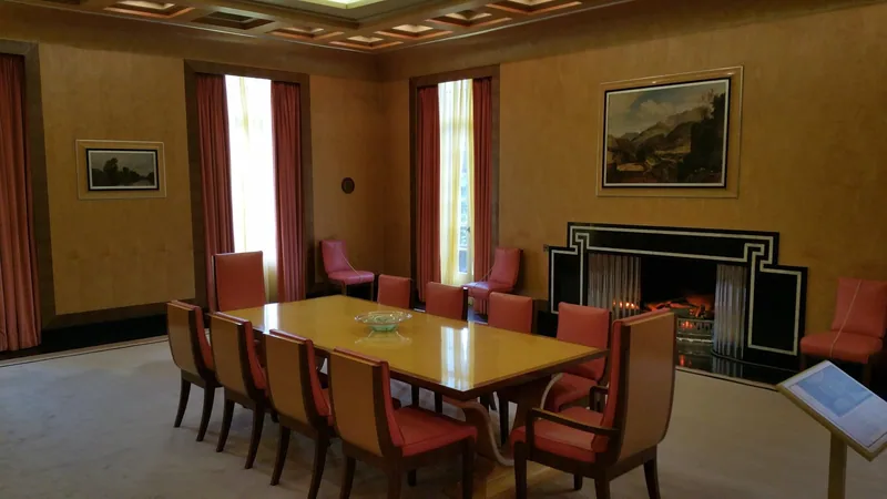 The 1930s Art Deco dining room at Eltham Palace with its lacquered table, pink leather chairs and black marble fireplace