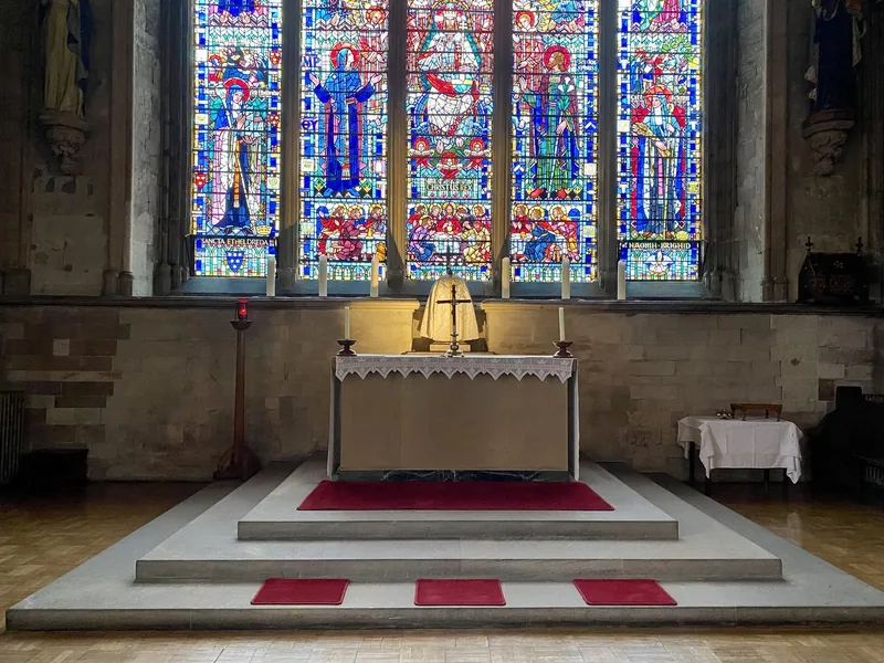 The stone altar of St Etheldreda's Church below its brightly coloured stained-glass east window