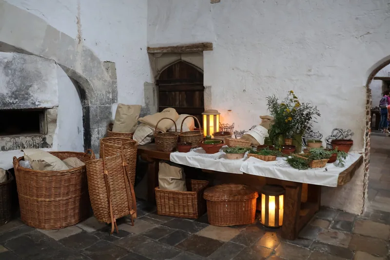 Wicker baskets, herbs and lanterns set out on a trestle table in the Tudor kitchens at Hampton Court