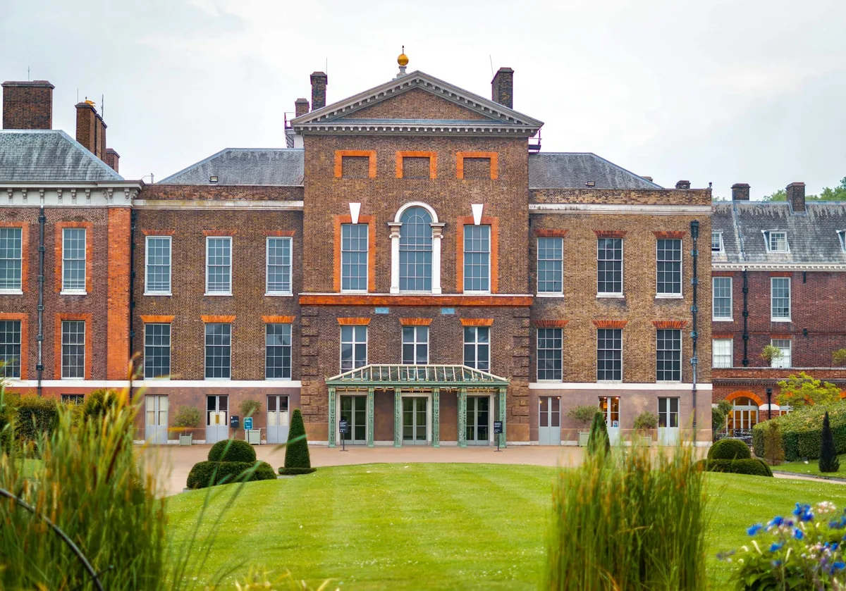 The red-brick south front of Kensington Palace behind a lawn and ornamental grasses