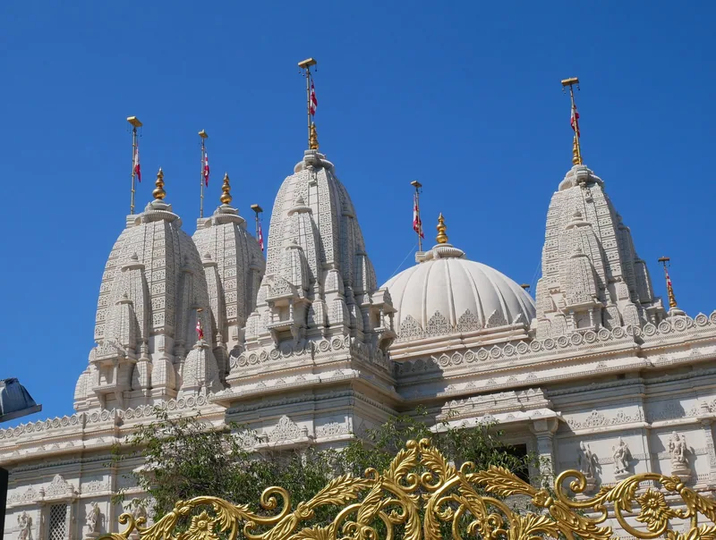 Carved marble spires on the east face of the Neasden temple, seen over a gilded ornamental gate