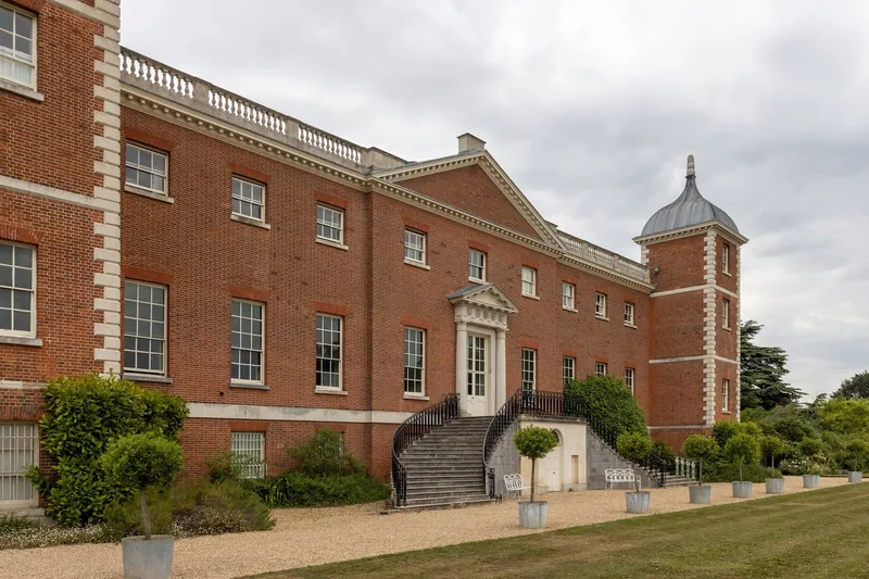 The garden front of Osterley House, with a curved stone stair up to the door and potted bay trees