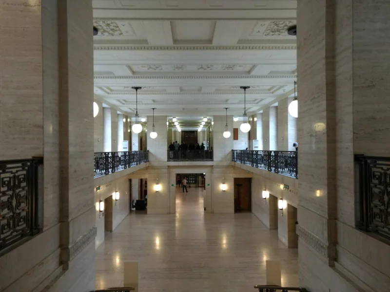 The stone-lined entrance hall inside Senate House, with globe lamps, a gallery above and Art Deco ironwork balustrades