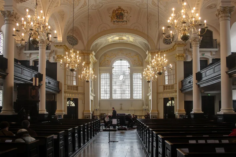 Inside St Martin-in-the-Fields, looking down the wooden pews to the east window beneath a barrel-vaulted ceiling