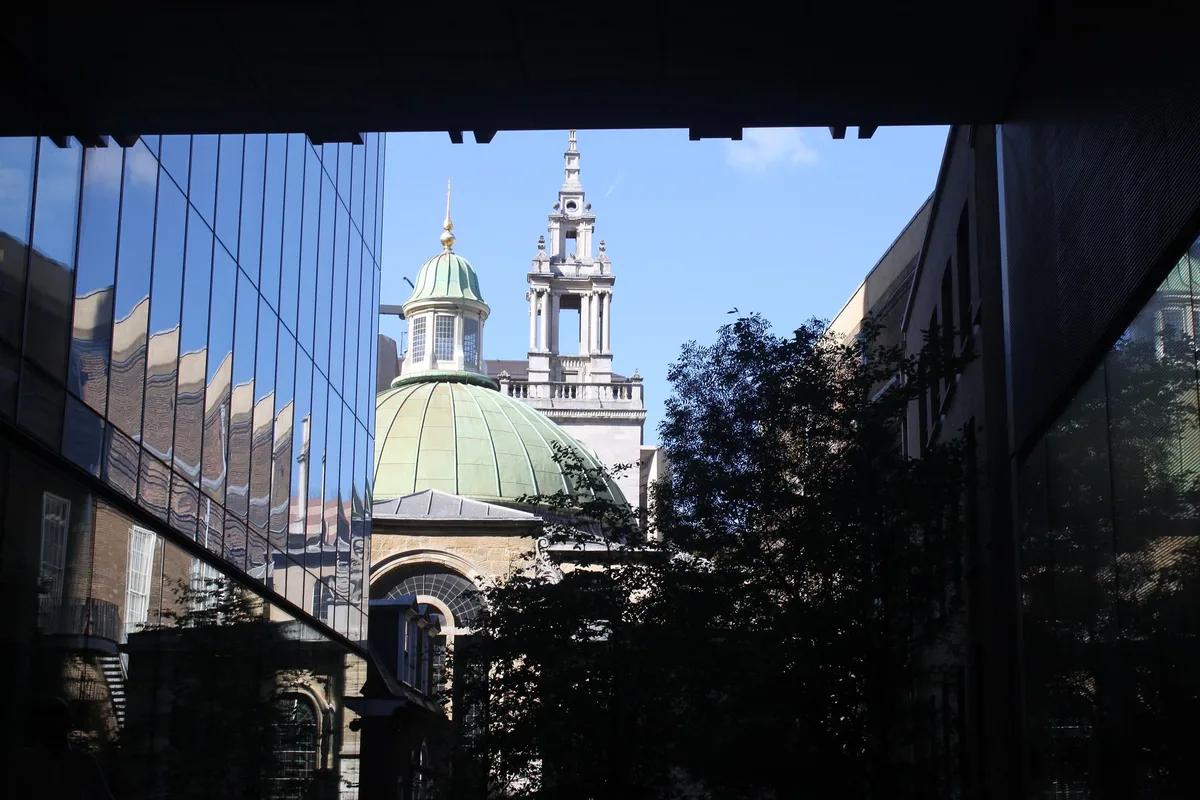 Green copper dome and stone steeple of St Stephen Walbrook framed by glass City offices