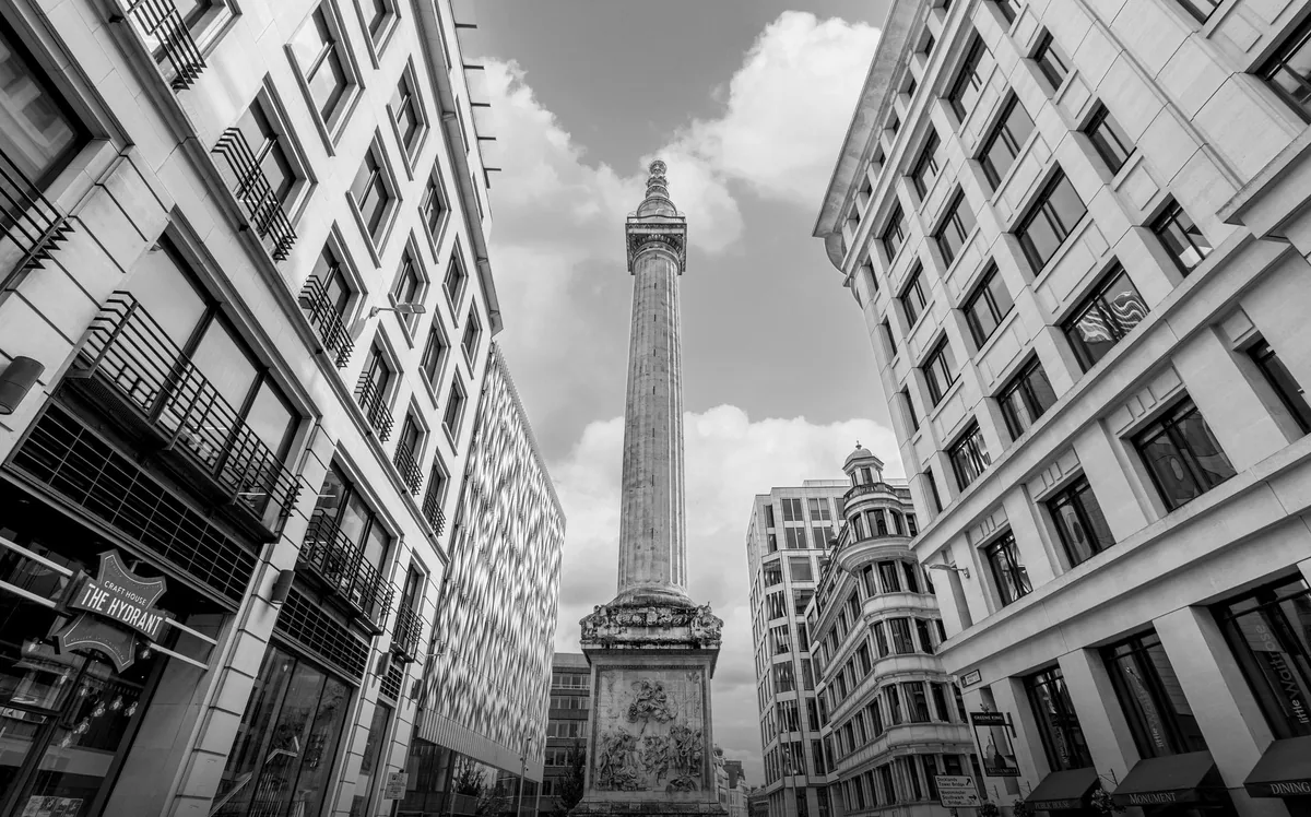 The tall fluted column of the Monument to the Great Fire of London rising between City office blocks