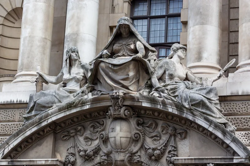 Carved stone figures above the main entrance of the Central Criminal Court, flanking a shield and scrollwork