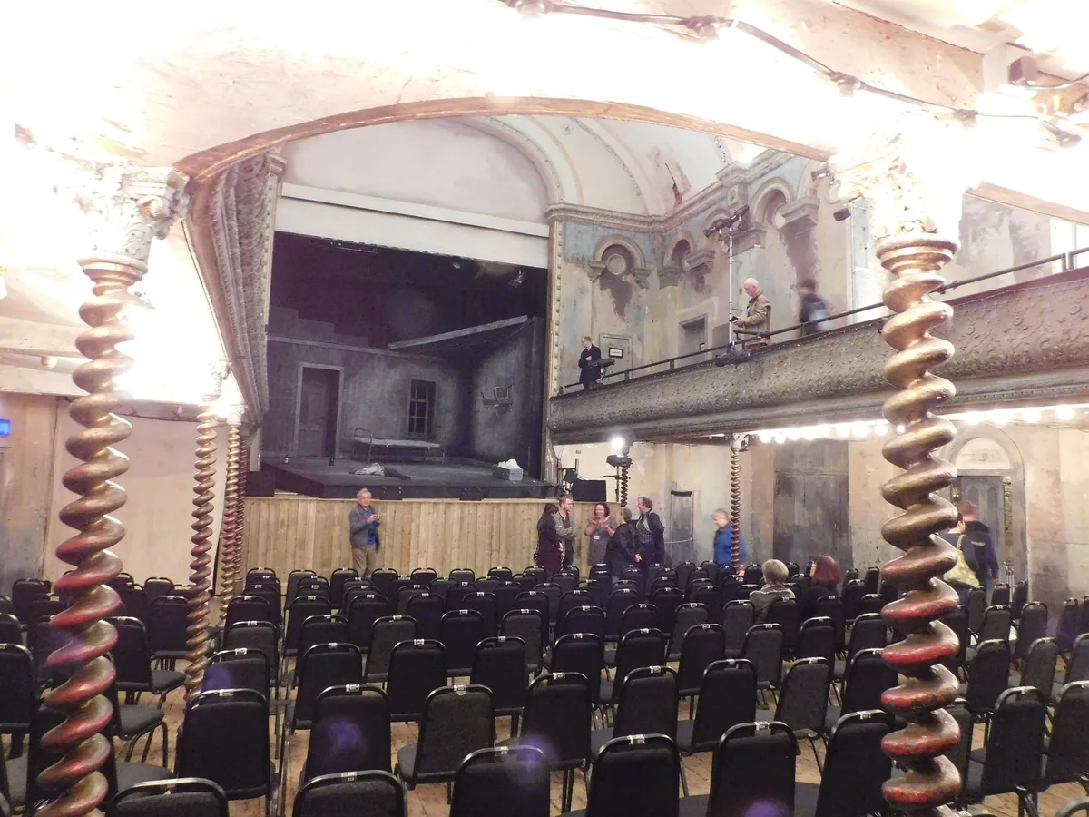 The auditorium of Wilton's Music Hall, with barley-sugar columns, bare plaster walls and rows of chairs facing the stage