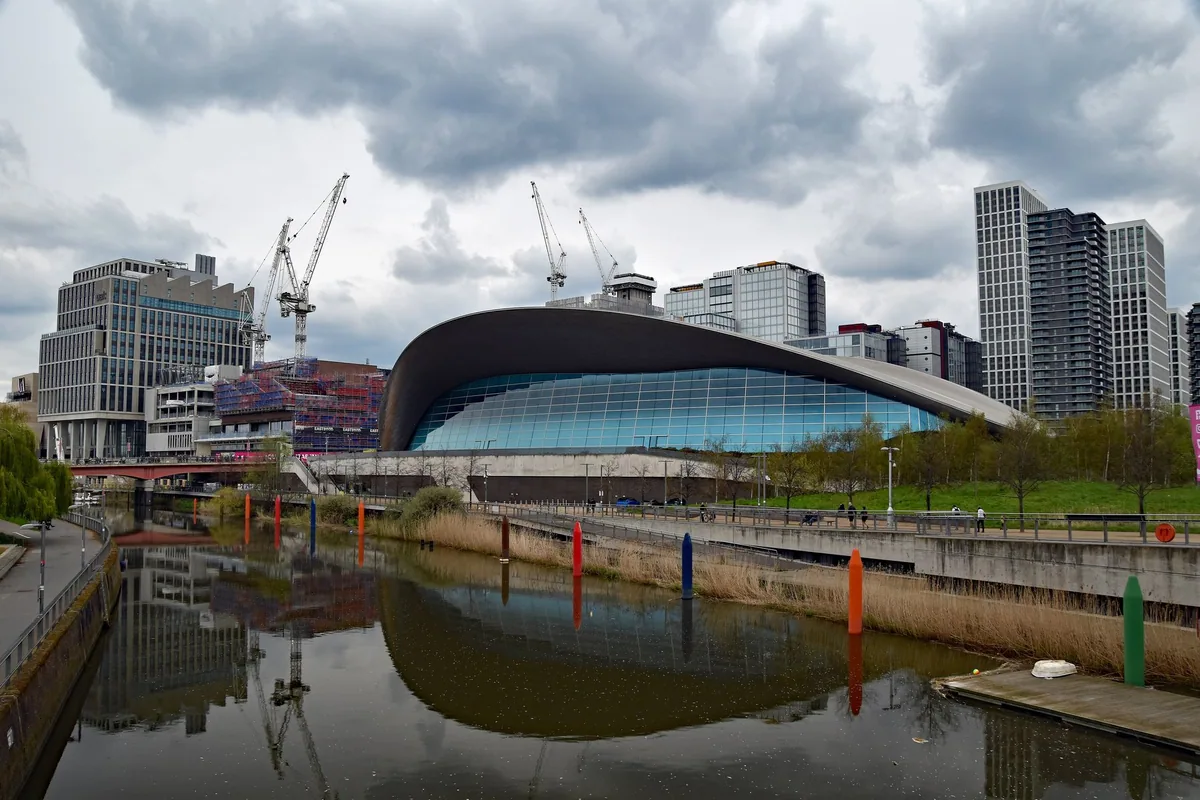The wave roof of the London Aquatics Centre above the canal, with new Stratford towers behind
