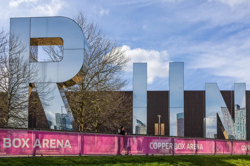 Mirrored RUN letter sculpture standing in front of the dark-clad Copper Box Arena