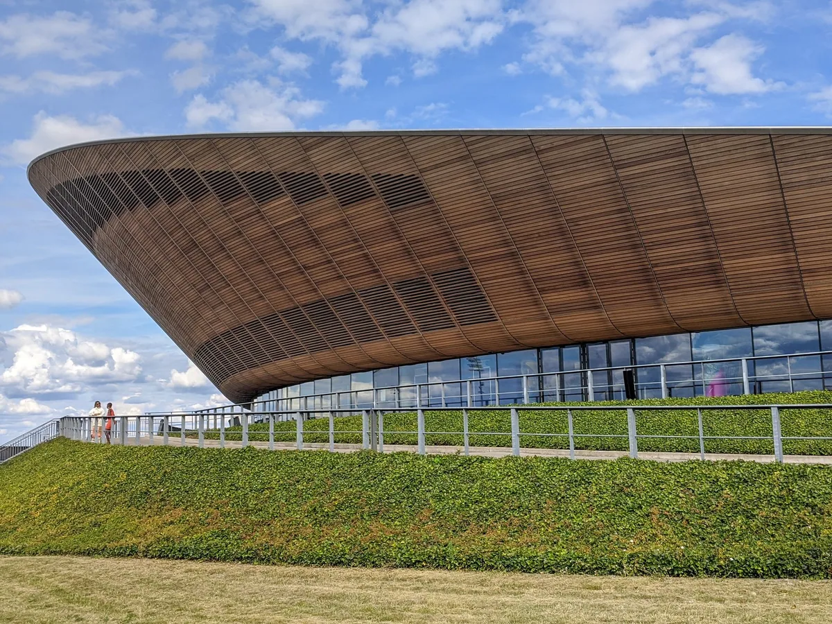 Curved timber-clad roof of the Lee Valley VeloPark velodrome above its green bank