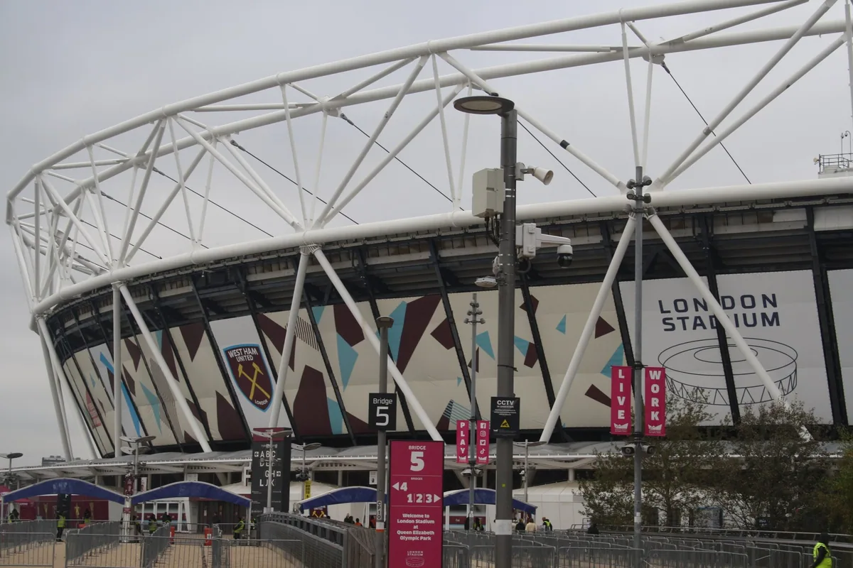 Outside the London Stadium, with its steel roof truss and a London Stadium sign on the wrap
