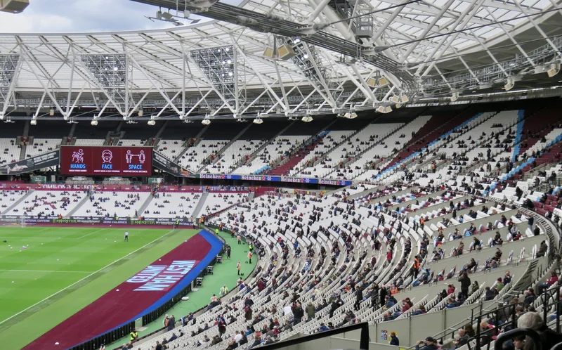 Inside the London Stadium before a West Ham match, with claret seats around the pitch under the roof