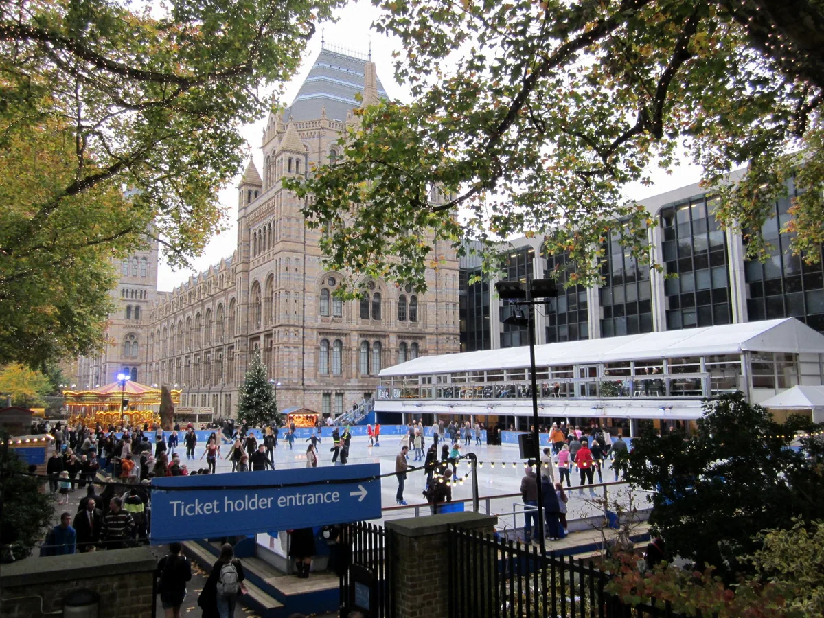 Skaters circling the open-air ice rink outside the Natural History Museum, with the terracotta building behind