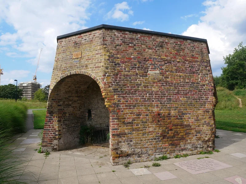 The restored brick lime kiln in Burgess Park, a square block with a deep arched opening, standing on a paved circle