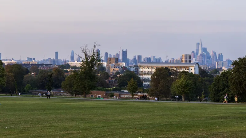 View across the wide grass slopes of Brockwell Park towards the distant towers of the City of London