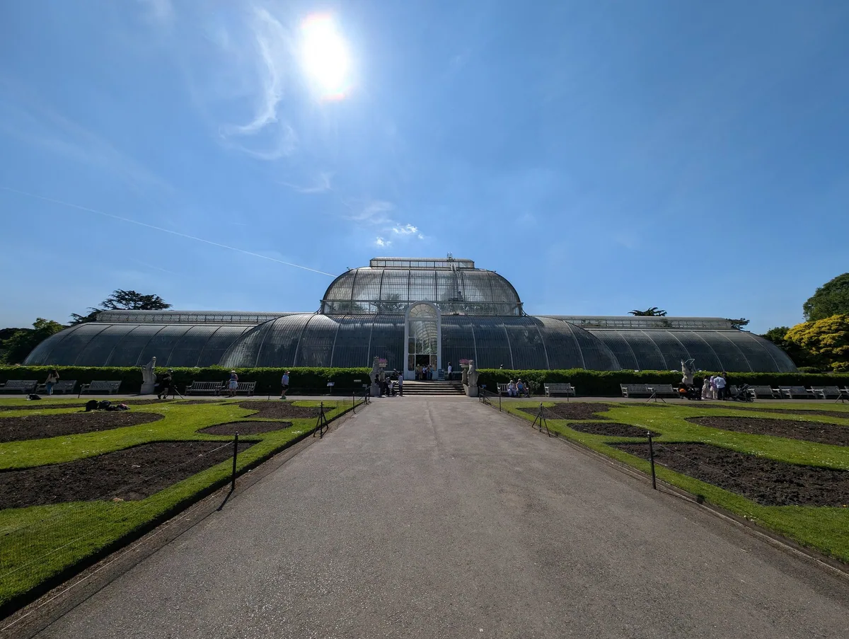 The glasshouse front of the Palm House at Kew Gardens, seen straight down the gravel walk across the parterre