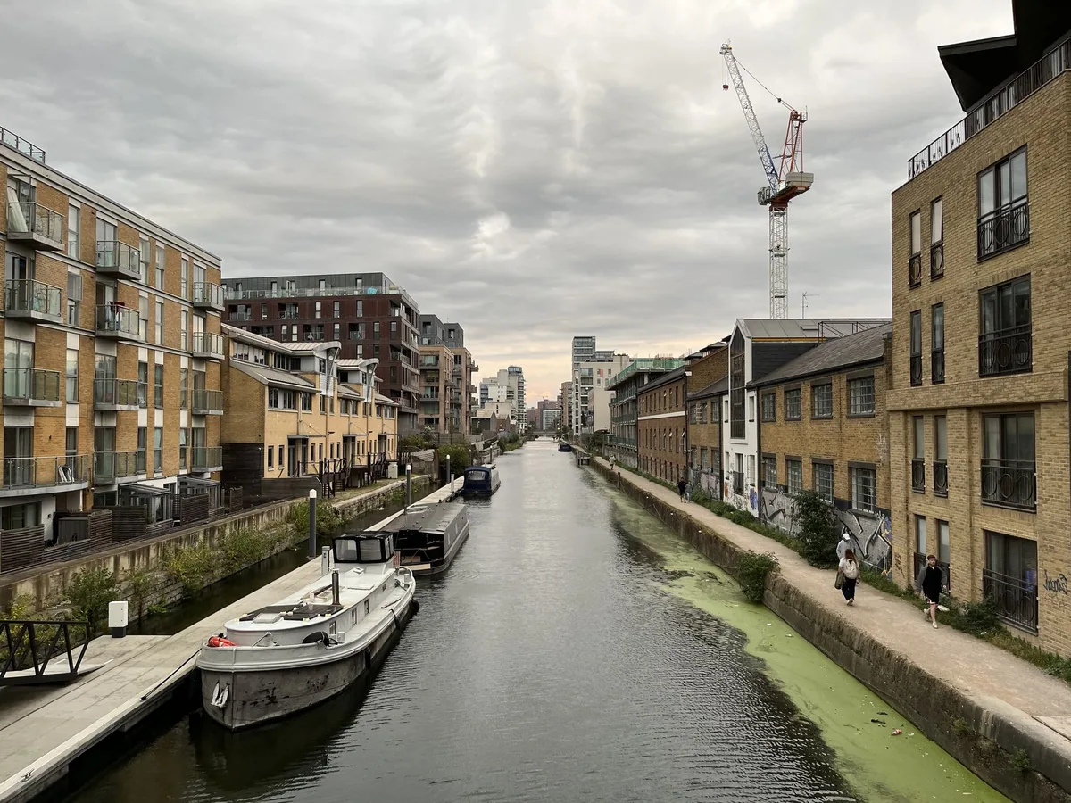 The dead-straight Limehouse Cut running away between blocks of flats and old warehouses, narrowboats moored along the left bank