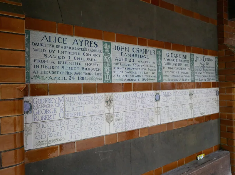 Row of glazed ceramic tablets on the Memorial to Heroic Self-Sacrifice, each naming an ordinary person who died saving another