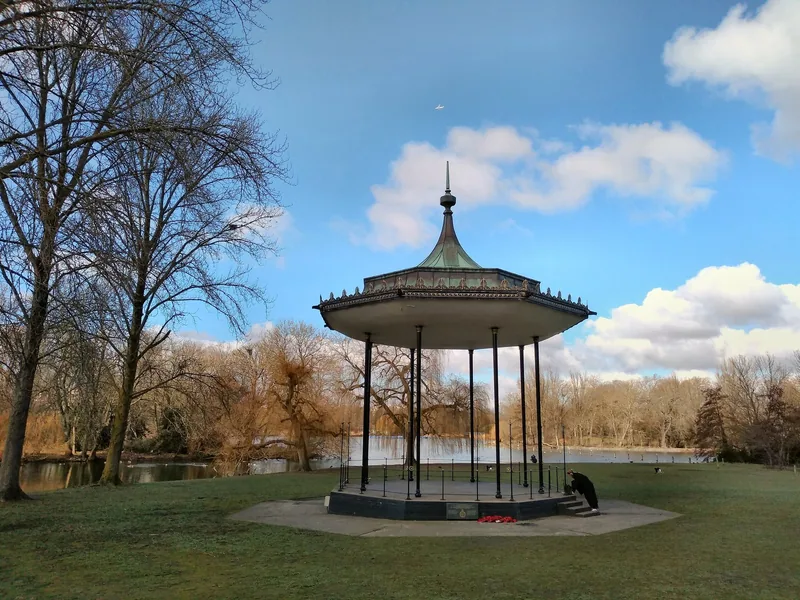 The ornate bandstand in Regent's Park beside the boating lake under a blue sky