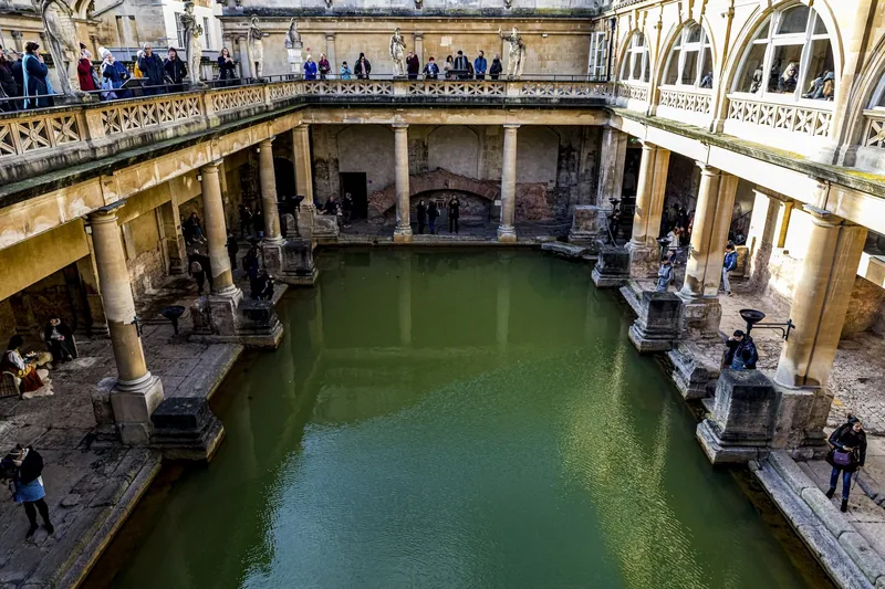 The green water of the Great Bath at the Roman Baths, ringed by columns and terraces